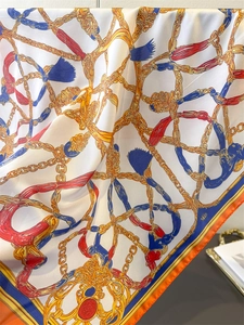 Detailed texture of retro chain print silk scarf with orange border and satin luster