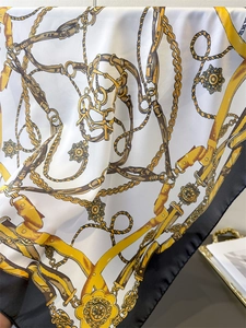 Detail of vintage luxury silk scarf featuring golden chains and medallion print patterns