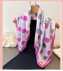 Détail d'un foulard en soie avec pois floraux et imprimé éléphant sur bordure rose