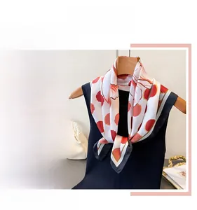 Détail d'un foulard en soie imprimé floral et à pois avec une bordure contrastée