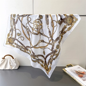 Detail of silk scarf with baroque gold chain and vintage floral pattern hanging elegantly