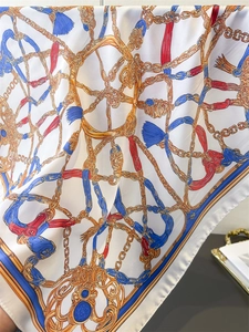 Close-up of vintage chain print silk scarf showing smooth texture and golden details
