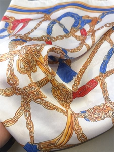 Detail of vintage chain and horsebit print on smooth silk scarf with vibrant colors