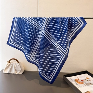Detail eines blau-weißen Seidenschals mit Polka-Dots und edler Textur in Nahaufnahme
