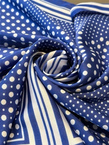 Detailaufnahme eines Seidenschals mit blau-weißen Punkten und gestreiftem Rand