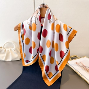 Carré en soie à pois avec bordure orange sur cintre, écharpe élégante et moderne
