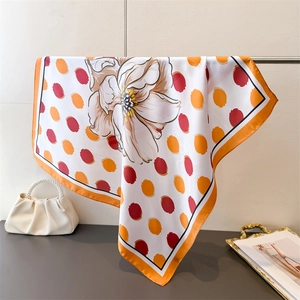 Vue détaillée du foulard en soie à pois floraux avec texture lisse et bordure orange vif