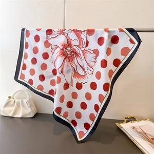 Détail d'un élégant foulard carré en soie à imprimé floral rouge et pois sur blanc