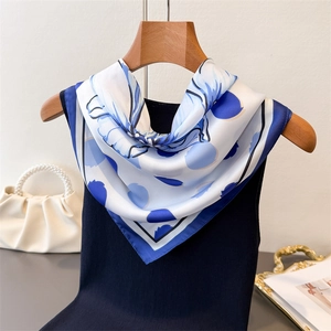 Détail du foulard en soie à pois et fleurs drapé sur un cintre en bois élégant