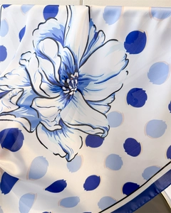 Détail d'un foulard en soie avec imprimé floral bleu, pois et texture satinée douce