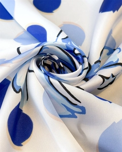 Détail d'un foulard en soie à fleurs montrant une texture lisse et un motif floral bleu