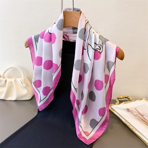 Foulard en soie à fleurs avec bordure rose drapé élégamment sur une chemise noire