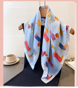 Détail d'un foulard en soie bleu clair orné de motifs teckels colorés sur un cintre