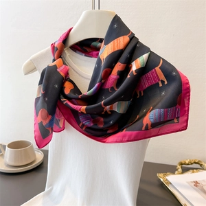 Détail d'un foulard en soie imprimé avec teckels et bordure magenta sur un mannequin de mode