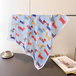 Détail d'un foulard en soie bleu clair avec motifs de teckels colorés en dessin