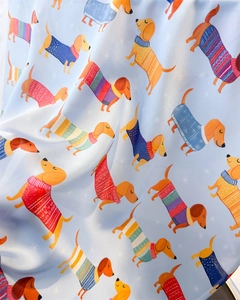 Détail d'un foulard en soie synthétique bleu clair avec des teckels en pulls festifs