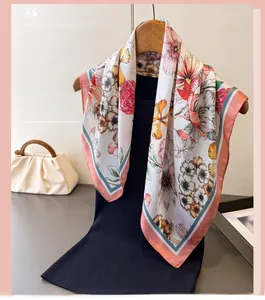 Close-up of floral silk scarf with colorful prints and pink teal borders on a hanger