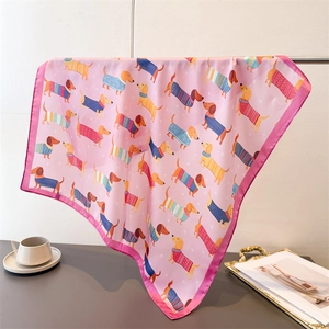Carré en soie rose avec motifs de teckels suspendu sur un support d'exposition