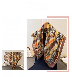 Detail of silk scarf with leopard print and orange chain patterns on satin fabric