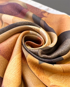 Makroaufnahme eines Seidenschals mit orangefarbenen Mustern und glatter Satingewebe-Textur