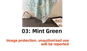 Close-up of mint green faux silk scarf with white magnolia print and rolled edges