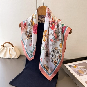 Elegant floral silk scarf with red and yellow flowers draped on a wooden hanger with bag