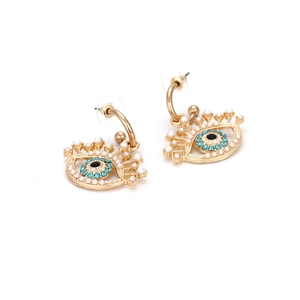 Détail de boucles d'oreilles œil porte-bonheur dorées avec strass et perles