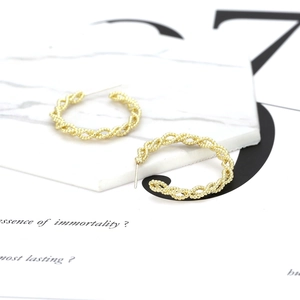 Elegant gold twisted bead C-hoop earrings displayed on a white marble tray stand