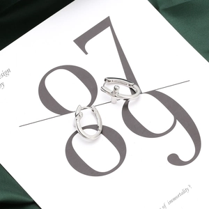 Polished silver cross drop hoop earrings presented on a minimalist white art card