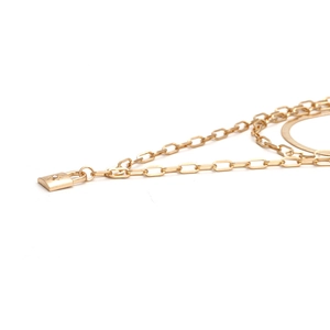 Layered gold necklace featuring flat snake chain and padlock pendant with starburst motif
