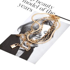 Layered gold snake chain necklace with rectangular star-engraved padlock pendant