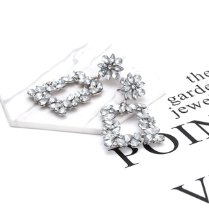 Macro shot of vintage silver earrings featuring intricate floral crystals and hollow details