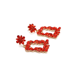 Detail of vintage gold flower earrings featuring vibrant red rhinestones in a hollow frame