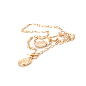 Détail d'un collier chaîne dorée avec pendentif pièce vintage et fermoir à bascule OT