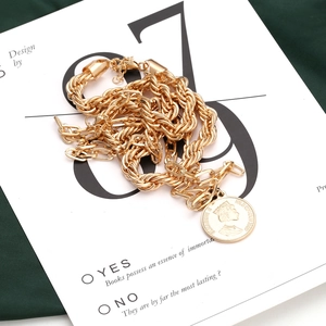 Chunky gold chain necklace with vintage 1989 coin pendant on green silk fabric