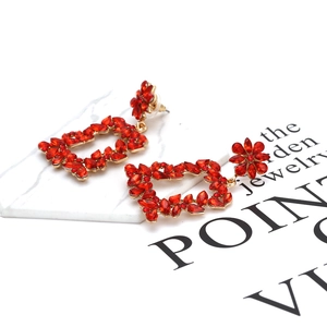Detail of vintage gold flower drop earrings with red crystal rhinestones on marble