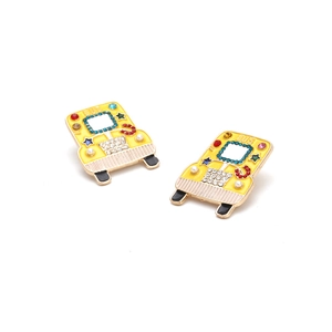 Macro detail of yellow enamel school bus earrings with colorful rhinestones and pearls