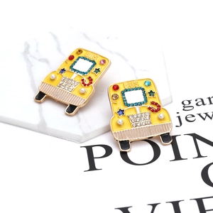 Vibrant yellow bus stud earrings with colorful rhinestones and enamel on marble surface
