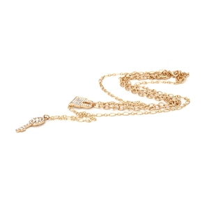 Détail du collier doré multi-rangs avec pendentifs clé et cadenas sertis de strass