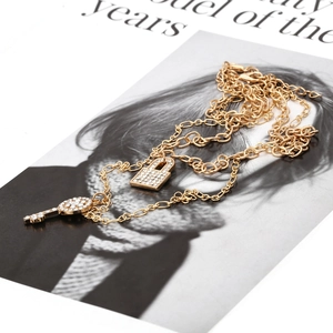 Détail du collier doré avec pendentifs serrure et clé sertis de cristaux sur magazine