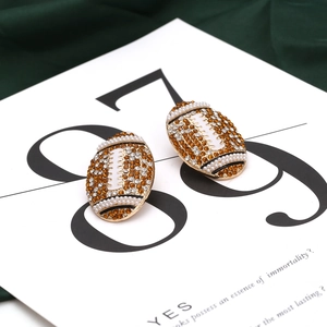Détail de boucles d'oreilles football américain avec strass ambre et perles blanches