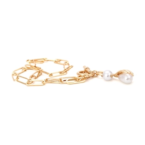 Dettaglio della collana dorata a catena con ciondolo di perla bianca e chiusura a T