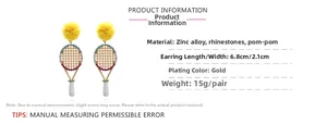 Détail des boucles d'oreilles raquette de tennis dorées avec pompon jaune et strass