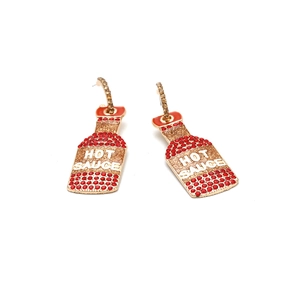 Dettaglio degli orecchini a forma di salsa piccante con strass rossi e smalto creativo