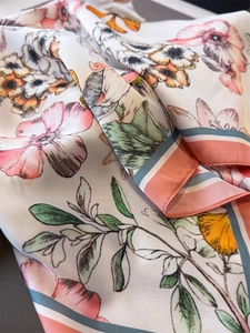 Detail of floral silk scarf showing satin texture and hand-painted botanical patterns