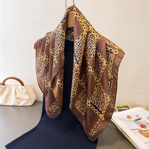 Elegant leopard and gold chain print silk scarf styled on a hanger with fashion props
