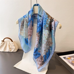 Detailed close-up of blue and white floral silk scarf draped on a white hanger