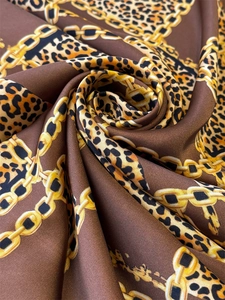 Macro detail of silk scarf featuring elegant leopard print and golden chain patterns