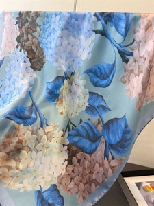 Detail of silk-like satin scarf with elegant blue hydrangea floral print and soft drape