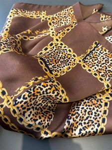 Detailed macro of silk square scarf featuring classic leopard and golden chain print